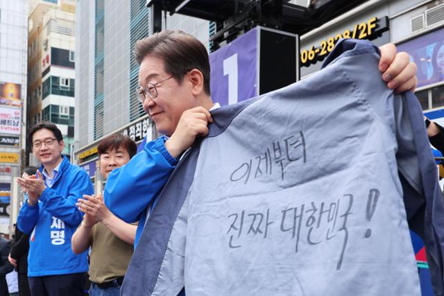 이재명 더불어민주당 대선 후보가 민주당 험지로 꼽히는 부산·경남(PK) 지역 유세에 나선 14일 경남 창원시 상남분수광장에서 열린 집중유세에서 송순호 경남도당위원장으로부터 이제부터 진짜 대한민국! 문구가 써진 작업복