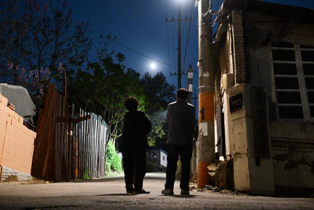11일 '백사마을' 1통에 거주하는 박귀순(75)씨 니트공장 부부가 보름달을 바라보며 서있다. 최주연 기자