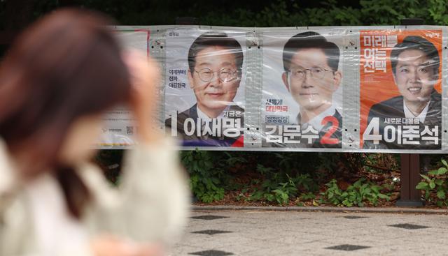 제21대 대선을 열하루 앞둔 23일 서울 마포구 공덕오거리 인근에 걸린 대선 후보 벽보 앞으로 시민이 지나가고 있다. 연합뉴스