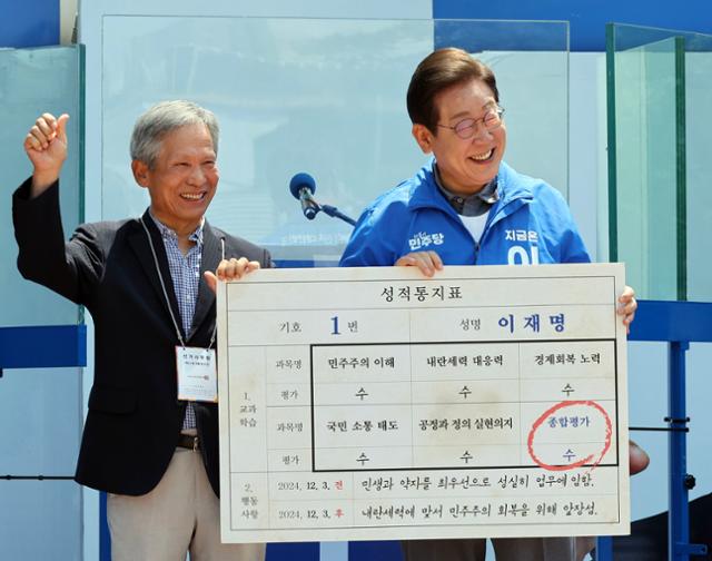 이재명 더불어민주당 대선 후보가 1일 오전 경북 안동시 웅부공원에서 유세 전 초등학교 은사인 박병기 씨로부터 성적표를 받고 있다. 안동=고영권 기자