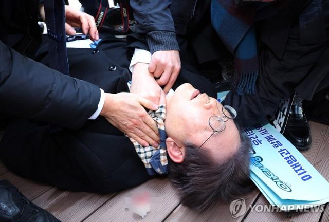 이재명 대선 후보가 당대표 시절이던 2024년 1월 2일 오전 부산 강서구 가덕신공항 부지를 둘러본 뒤 왼쪽 목 부위 피습을 당해 바닥에 누워 병원 이송을 기다리고 있다. 연합뉴스