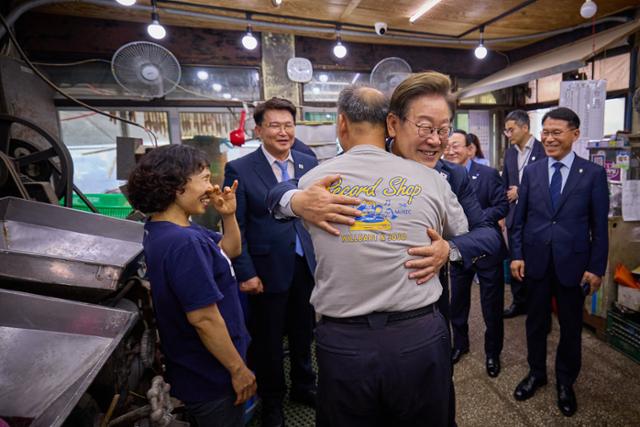 이재명 대통령이 지난 13일 경기 연천군의 한 방앗간에서 기본소득 실시지역 현황을 점검하며 주인과 포옹하고 있다. 뉴스1