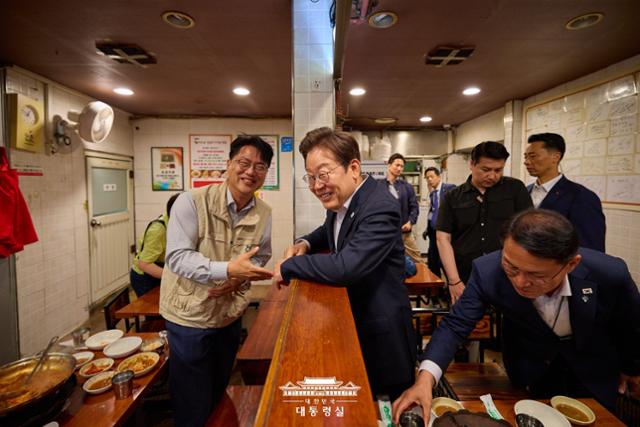 지난달 26일 서울 용산구 대통령실 인근 골목의 식당에서 점심식사를 한 이재명 대통령이 '방송 3법 개정'을 촉구하며 1인 시위를 하던 이호찬 전국언론노조 위원장을 우연히 만나 대화하고 있다. 대통령실 제공