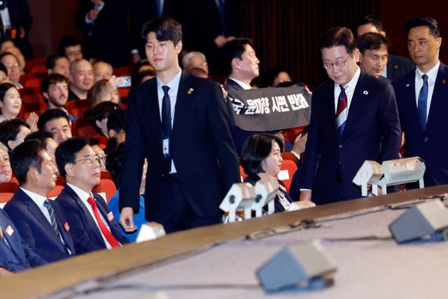 이재명(맨 앞줄 오른쪽) 대통령이 15일 서울 종로구 세종문화회관에서 열린 80주년 광복절 경축식에서 축사를 마친 뒤 1인 시위 중인 안철수(셋째 줄 가운데) 국민의힘 의원을 지나쳐 이동하고 있다. 연합뉴스