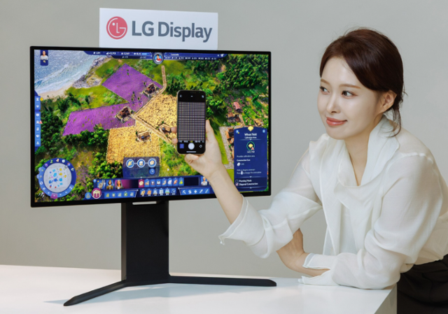 LG디스플레이 직원이 고주사율 모니터용 유기발광다이오드(OLED) 패널 앞에서 이 패널 내부에 적용된 RGB 스트라이프 픽셀 구조를 확대한 사진을 스마트폰으로 보여주고 있다.LG디스플레이 제공