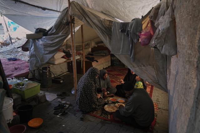 지난해 12월 25일 팔레스타인 가자지구 북부 알샤티 난민촌 천막 안에서 한 피란민 가족이 식사하고 있다.가자지구=AP 뉴시스