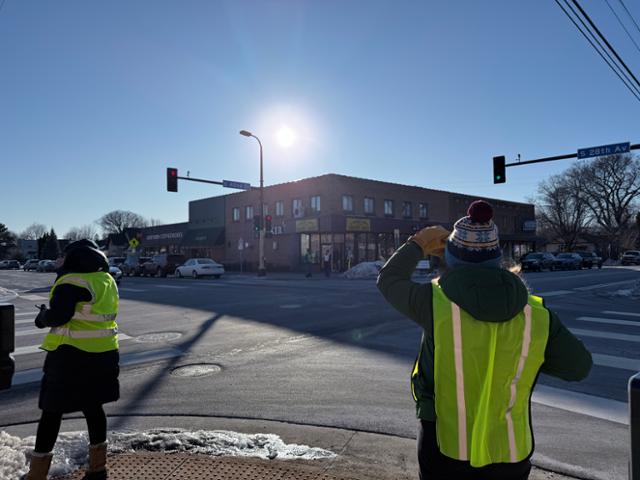 'ICE 감시단'을 자처한 학부모들이 14일 미 미네소타주 미니애폴리스의 한 공립학교 사거리에서 형광조끼를 입고 쉼 없이 주변을 살피고 있다. 최근 ICE는 이곳에서 자녀의 하교를 기다리는 학부모를 붙잡아갔다. 미니