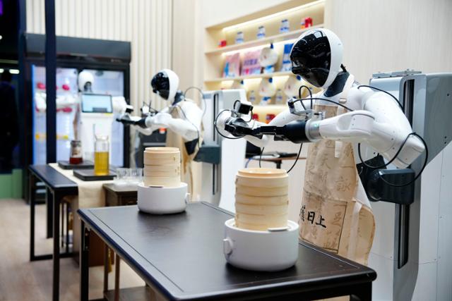 3일 스페인 바르셀로나에서 열린 MWC26 전시장에 설치된 차이나모바일의 휴머노이드 로봇들이 음식을 준비하는 동작을 시연하고 있다. 바르셀로나=EPA 연합뉴스