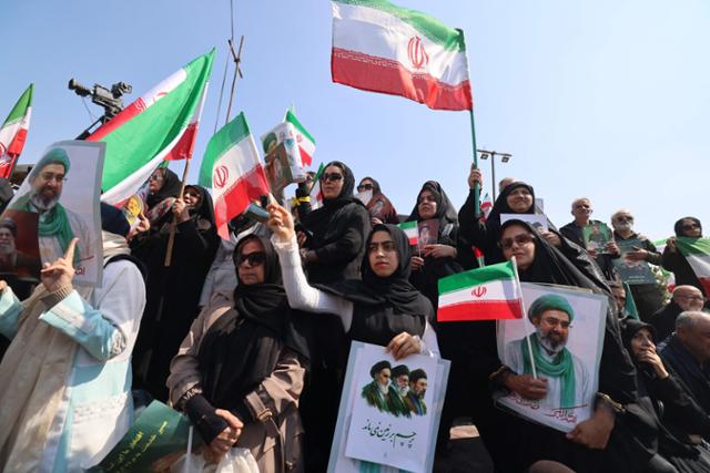 18일 이란 수도 테헤란에서 거행된 알리 라리자니 최고국가안보회의(SNSC) 사무총장과 이슬람혁명수비대 산하 바시즈 민병대의 골람레자 솔레이마니 총사령관의 장례식에 참석한 시민들이 이란 국기를 흔들고 있다.두 사람