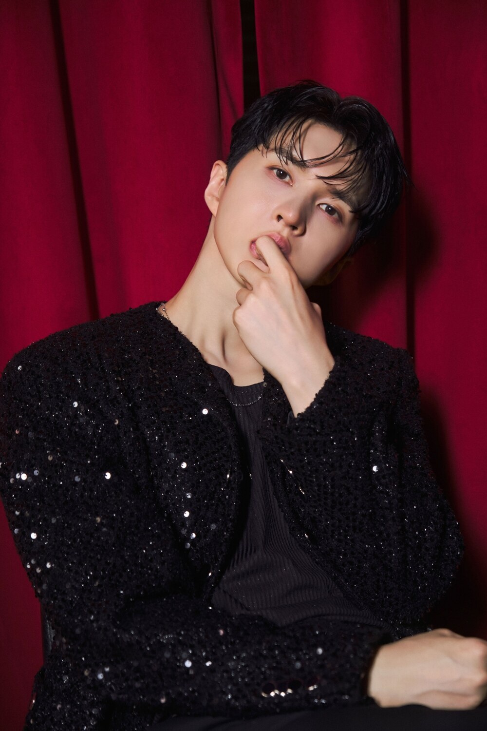赤いカーテンを背景に黒い衣装を着たVIXXのケン