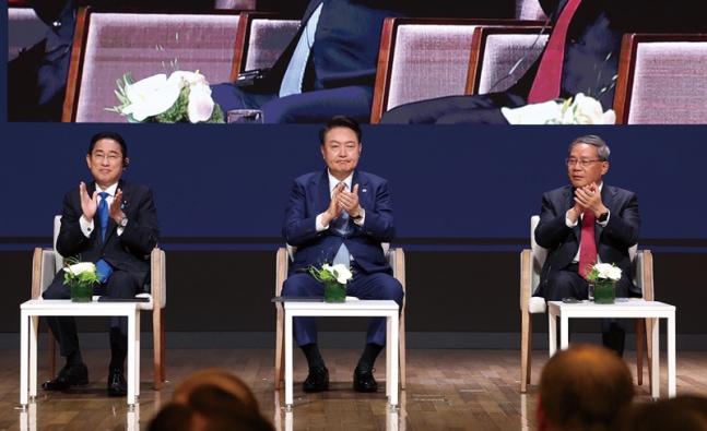 President Yoon Suk-yeol, Japanese Prime Minister Fumio Kishida (left), and Premier Li Keqiang of China (right) applaud after listening to the reports of the three countries' economic leaders during the 8th trilateral business summit of Korea, Japan, and China held at the Federation of Korean Industries in Jung-gu, Seoul on May 27