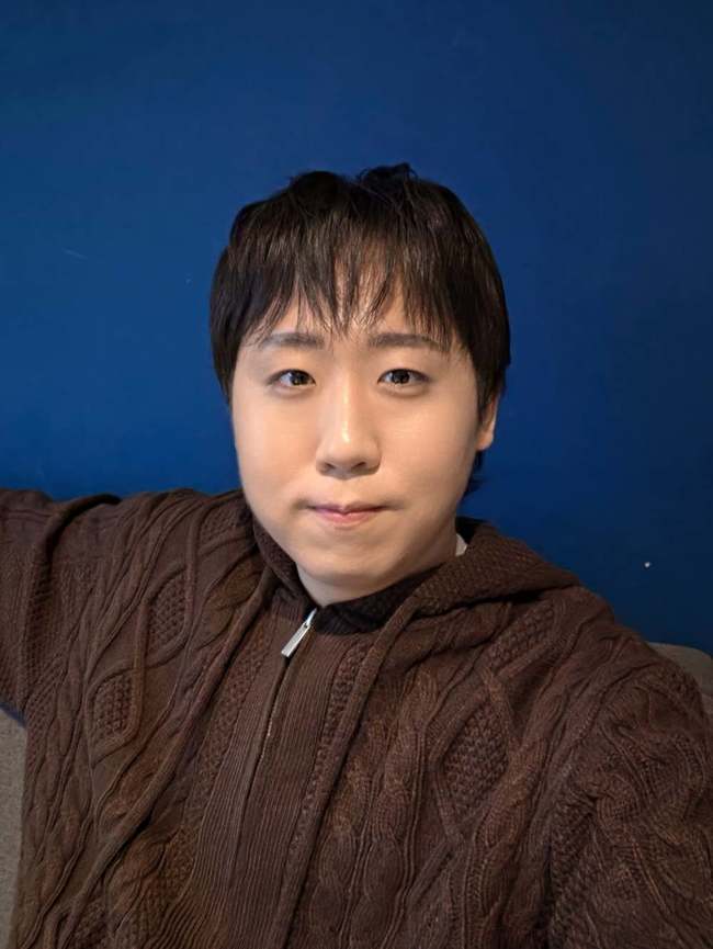 青い壁を背景に自撮りをするコメディアンのイ・ジェユル