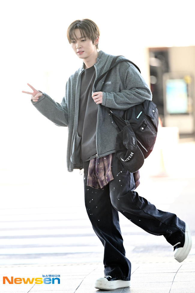 グレーのパーカー姿で空港に現れ、ピースサインをするStray Kidsのリノ