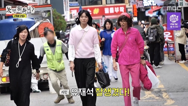市場を歩く女装姿のチュ・ウジェ。画面の字幕には市民の「ユ・ジェソク、かっこいい」という言葉が映る