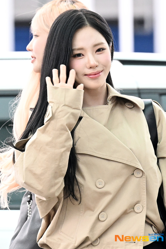 ベージュのトレンチコート姿で空港から手を振るfromis_9のパク・ジウォン