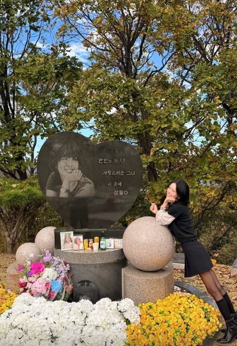 母チェ・ジンシルさんの墓碑のそばで、墓碑の写真と同じポーズを取るチェ・ジュンヒ