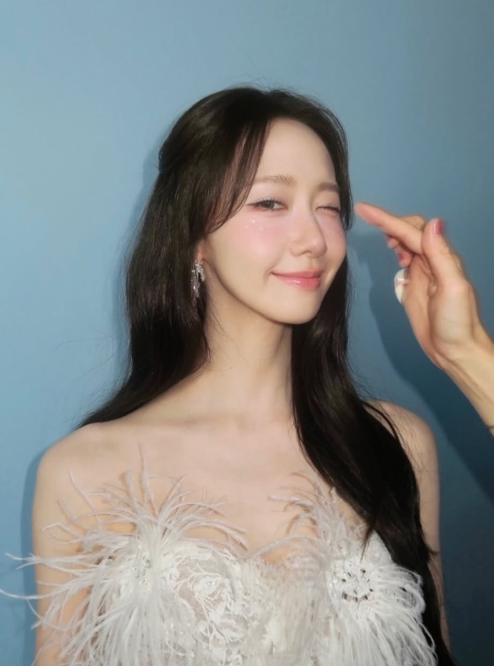 白い羽根飾りのドレスを着てウインクするイム・ユナ