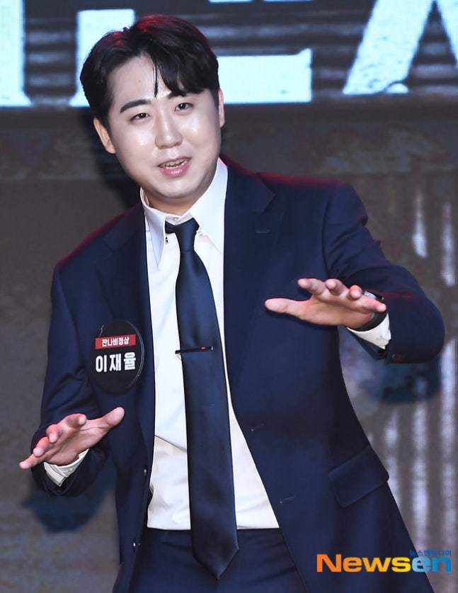 紺色のスーツ姿で手を広げて話すコメディアンのイ・ジェユル
