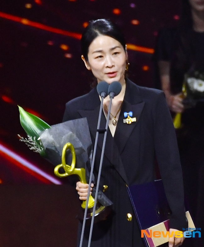大衆文化芸術賞の授賞式で、国務総理表彰を受けたイ・ジャラムが花束とトロフィーを手にマイクの前で話す様子
