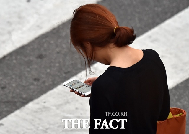 한 시민이 스마트폰을 보며 걷고 있다.사진은 기사 내용과 무관./더팩트 DB