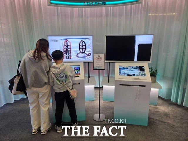지난 22일 서울 광화문 KT사옥 'KT 온마루' 전시관을 찾은 한 모자 방문객이 대한민국 통신 역사를 체험한 뒤 전시관 내에 설치된 'AI 라이브 드로잉'을 체험하고 있다./종로=우지수 기자