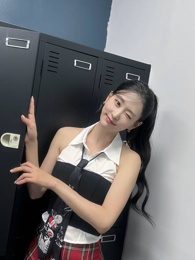 白いシャツと黒いビスチェ姿で笑顔を見せるキム・ウィヨン