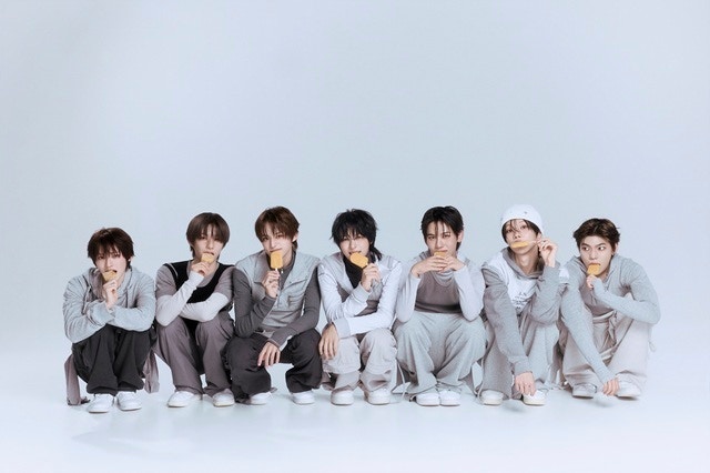 淡い色の衣装を着て横一列に座るYUHZの7人