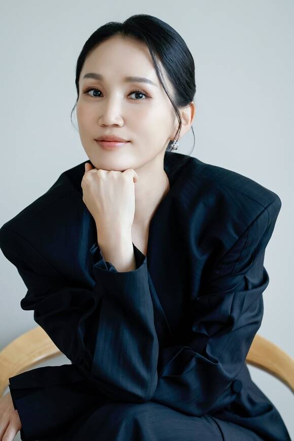黒い衣装で頬杖をつき、カメラに向かって微笑む俳優パク・ボギョン