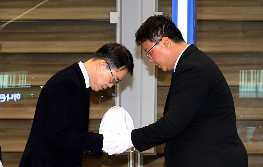Ahn Jung-man, chief of the Gyeongbuk Provincial Police Agency's criminal investigation unit, left, receives an urn conta