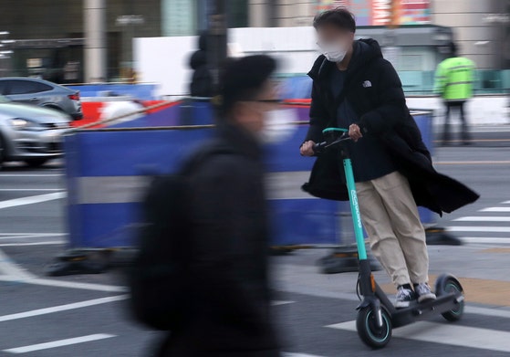 A commuter rides an e-scooter on the streets of Gwanghwamun, central Seoul, on Dec. 9, 2020. The pic