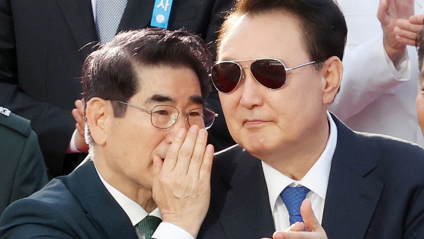 Former President Yoon Suk Yeol, right, listens to former Defense Minister Kim Yong-hyun during a mil