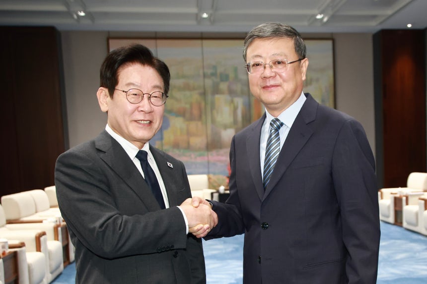 Korean President Lee Jae Myung, left shakes hands with Chen Jining, the Shanghai Municipal Party sec