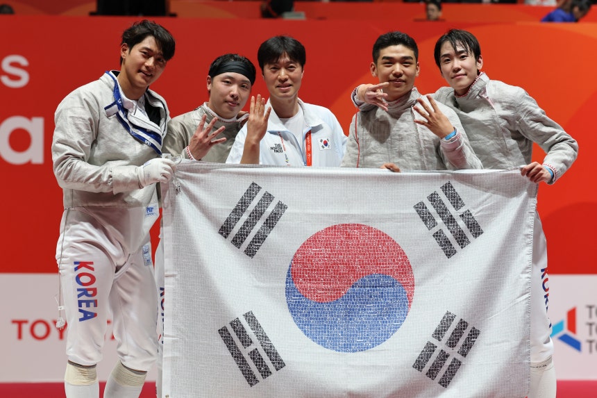 Korea's men's sabre team poses with the national flag after beating Japan in the team final at the Asian Games Aichi-Nag