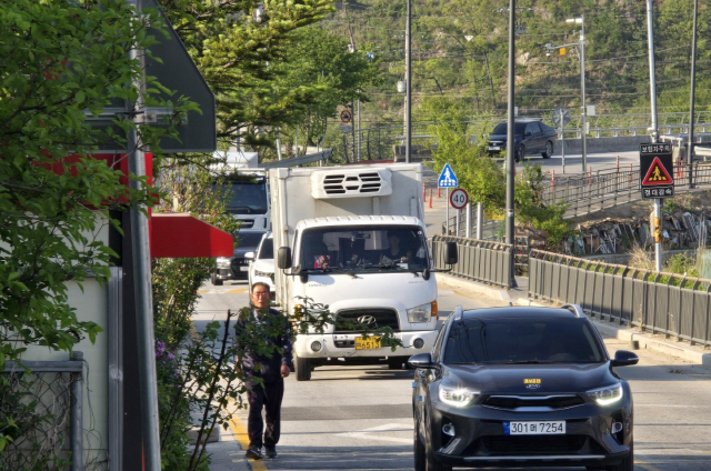 ▲ 원주 호저면 주산2리 학마을 앞 도로가 매일 출퇴근 시간대 차량들로 혼잡을 겪고 있다.6일 마을 주민이 차량 접촉 사고 등 위험을 감수하며 비좁은 도로변을 걷고 있다.