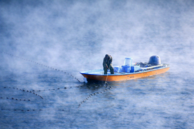 ▲ 6일 한파의 영향으로 물안개가 피어난 인제 소양호에서 어부가 조업을 하고 있다.인제군 제공