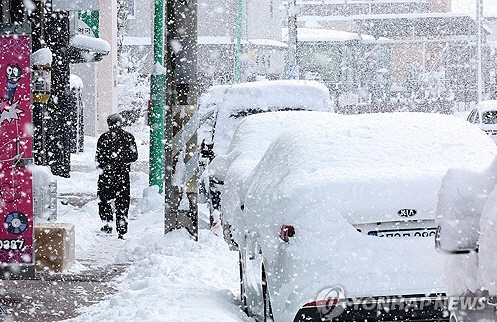 대설경보가 발효된 11일 전남 무안군 한 거리에서 주민이 눈을 맞으며 걸어가고 있다.  연합뉴스