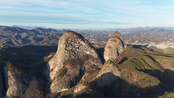 2026년 말띠 해에 찾은 전북 진안 마이산 전경.취재팀이 봉두봉 헬기장에서 남쪽으로 드론을 날려 담았다.두 암봉 중 타포니 현상으로 뻐꿈뻐꿈 구멍이 난 왼쪽이 암마이봉,그 오른쪽이 숫마이봉이다.가운데 V자 