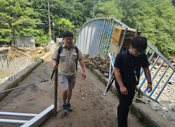 지게로 구호품 나르는 신희섭(왼쪽)·박수완(오른쪽) 주무관. 연합뉴스, 경기도 제공